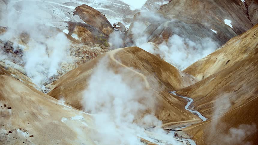 Winding trail through steaming hills with water flow in volcanic region