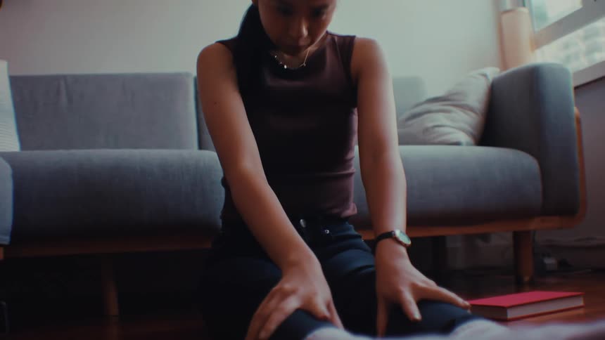 Woman performs seated stretching exercises with arms extended in a brightly lit room