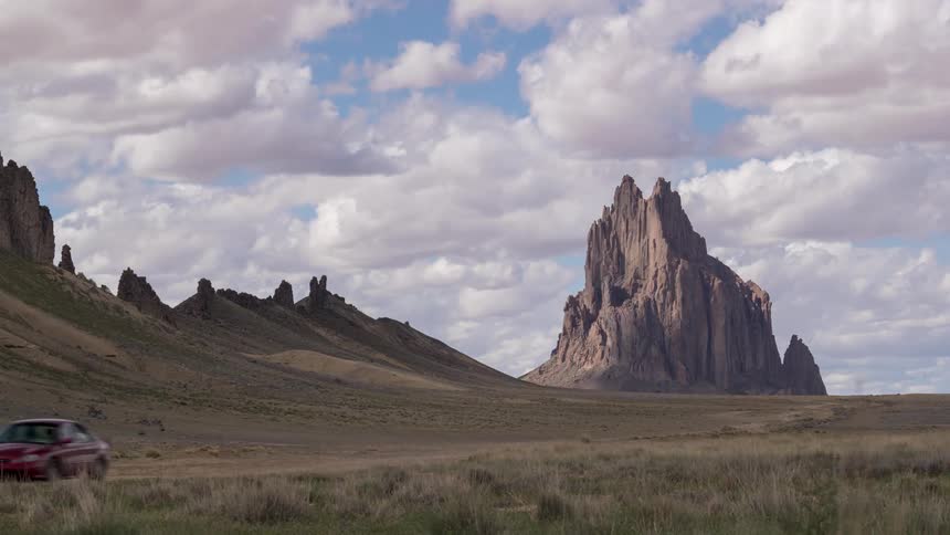 Car driving along a trail with mountains and cliffs
