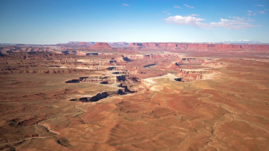 Canyonlands national park stretches out in a wide expanse of rocky terrain on a sunny day the bright light bringing out the warm colors