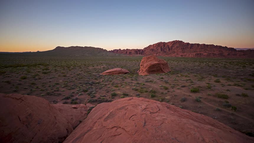 A valley with big rock formations and a grass path as the sun rises