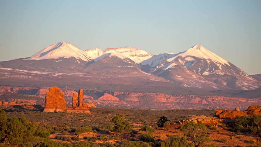 Buttes and red rock formations in the desert with mountains in the distance