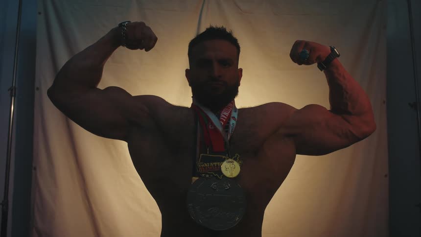 The man is flexing while wearing medals