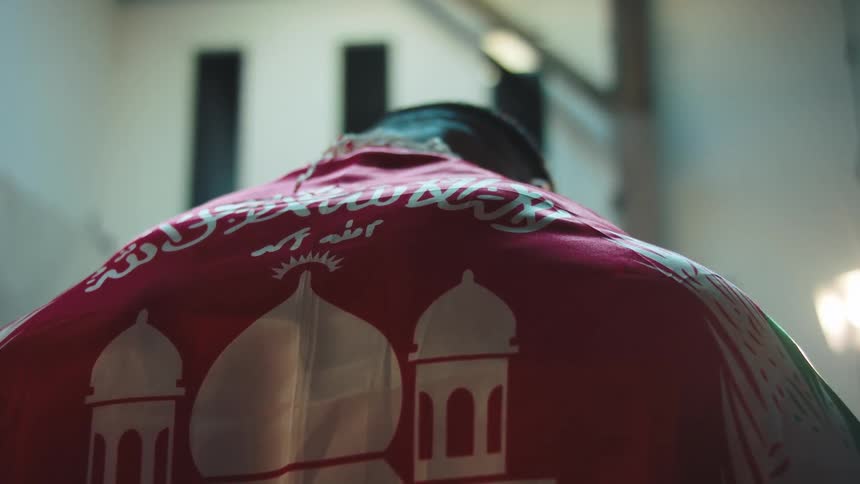 Person wrapped in a red flag with a mosque drawn on it
