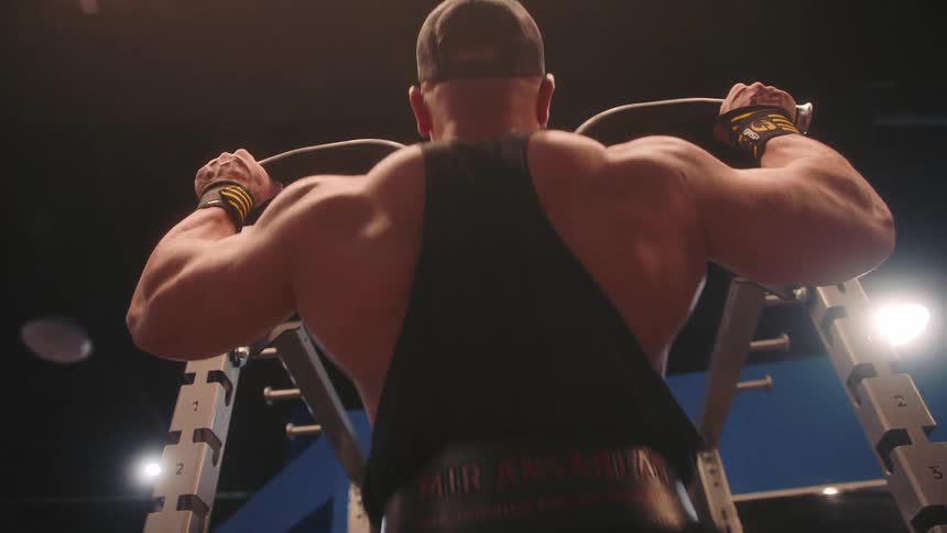 Man performs pullups on a strength training machine inside a gym