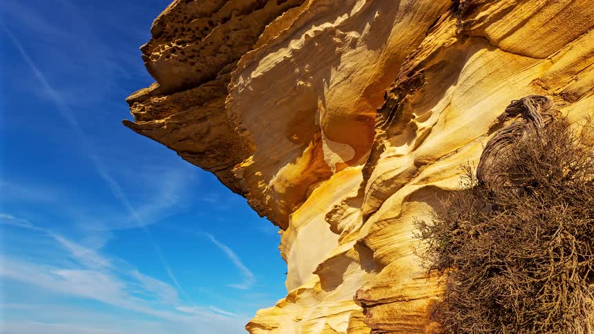 A large rocky formation rises in the canyon on a sunny day its rough surface catching the bright light