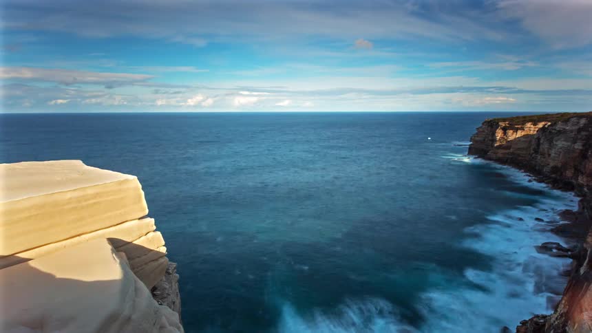 Waves crash against the cliffs
