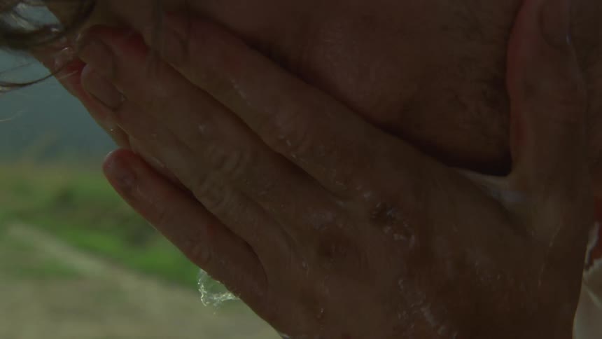 Face being washed with water dripping through the hands