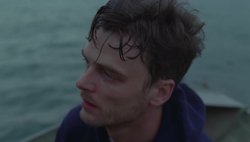 A man looks upset as he sits in a boat floating in the ocean