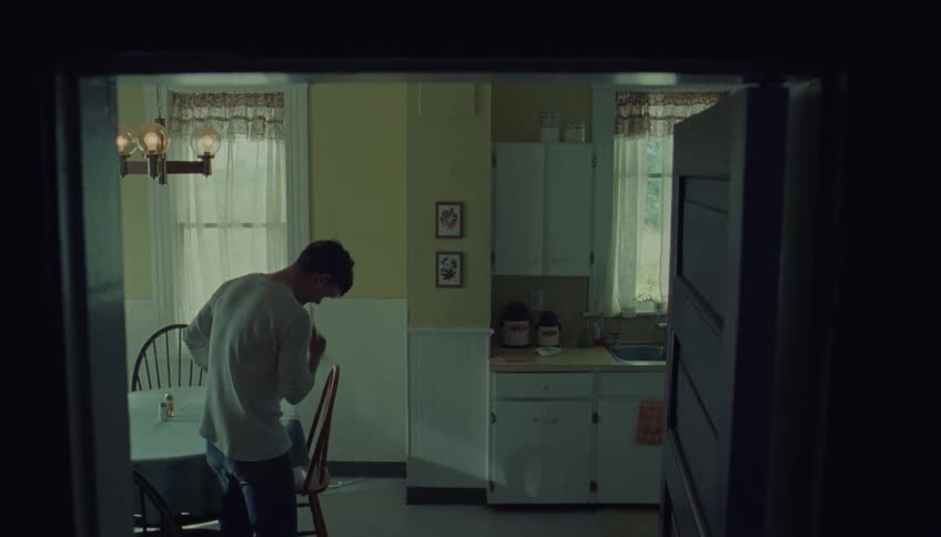 The man walks to the dining table and sits