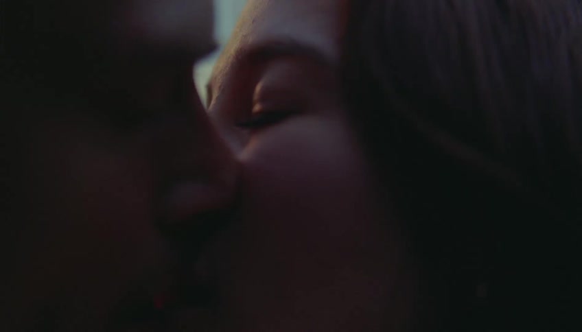 Couple kissing in closeup with partially lit faces