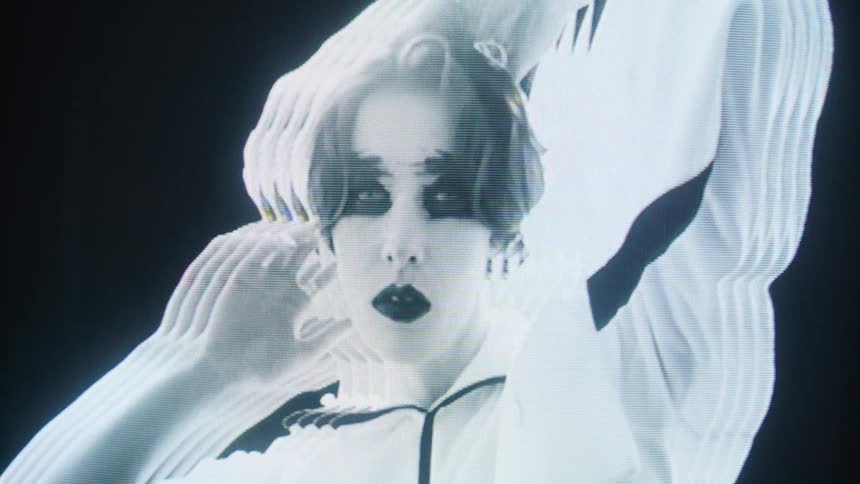 Woman with contrasting makeup and raised arms appears with a multiple exposure visual effect