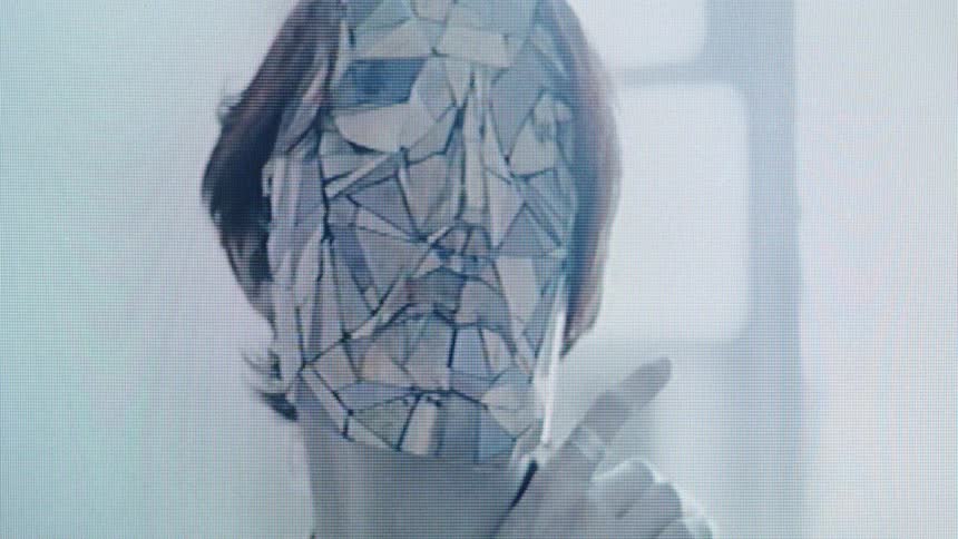 A persons face appears digitally shattered into a mosaic of geometric fragments