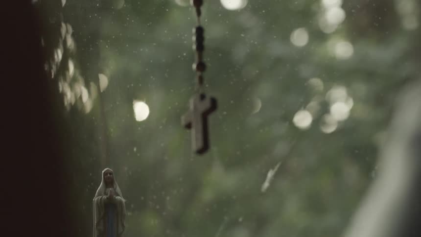 A view of a cross hanging from a rearview mirror in a car