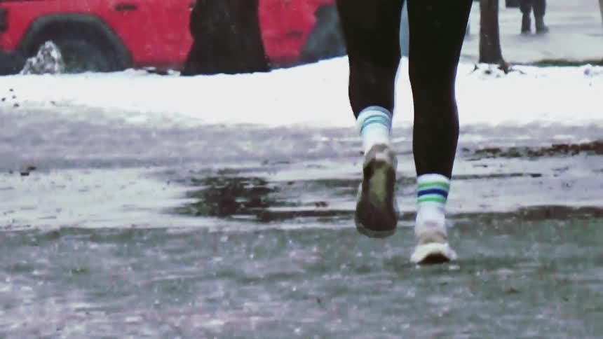 A woman is jogging outdoors while it snows