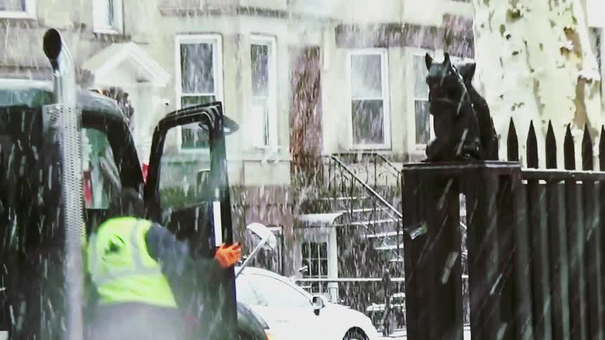 Garbage truck operating during snowfall in a residential area