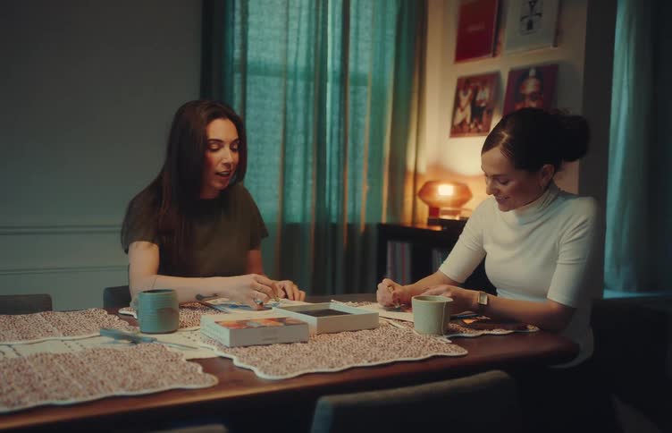 Two women talking while working on illustrations at a table with coffee cups
