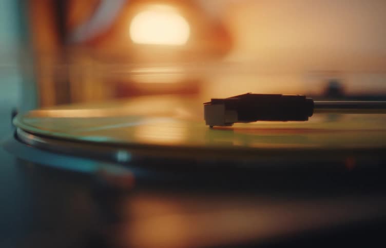 Closeup of a vinyl record spinning on a turntable under warm soft lighting