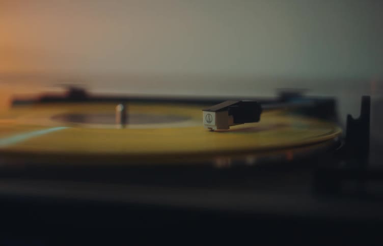 A closeup shot of a yellow vinyl record spinning on a turntable the needle remains steady in the groove as the record rotates under warm atmospheric lighting