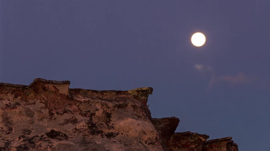 Full moon rising over a mountain at dusk