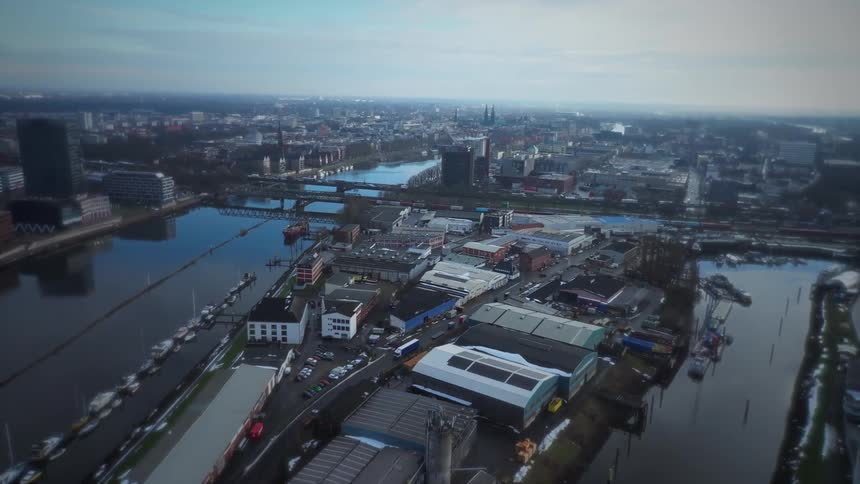 Straight edge of the pier on the left side of the frame where several white boats are moored in a neat row against the dark water horizontal bridge that spans across the water in the middle ground physically connecting the two sides of the city and cre