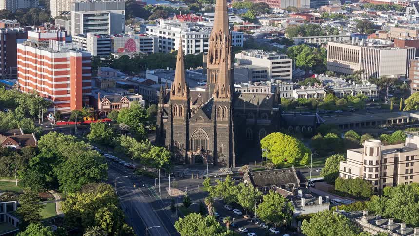 Time lapse of an urban city as vehicles drive past a brick cathedral