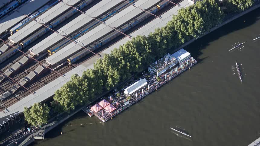 Floating structures with spectators along a river near railway lines seen from above
