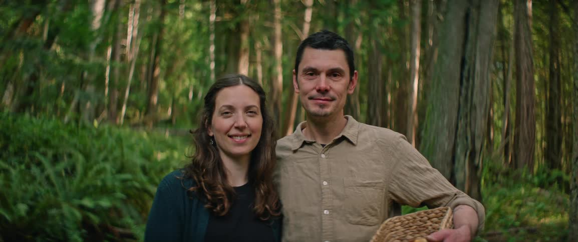 Couple standing together outside of the forest as he holds a basket