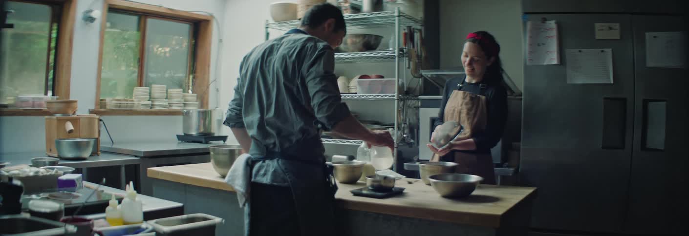 Two people working on food in a kitchen