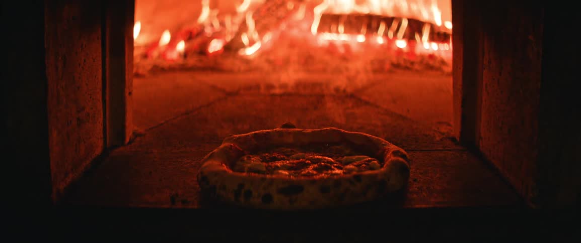 Pizza with puffed crust baking directly on woodfired oven stone