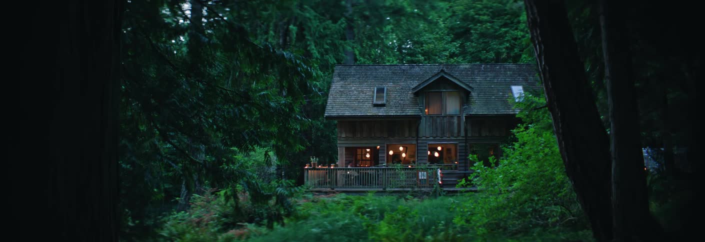 Person sitting on the porch of a cabin in the forest