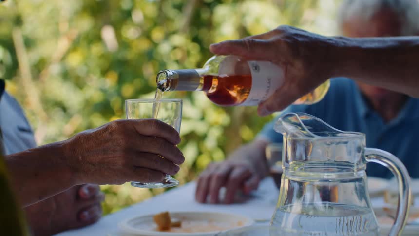 Ros wine being poured into a glass during an outdoor gathering among friends