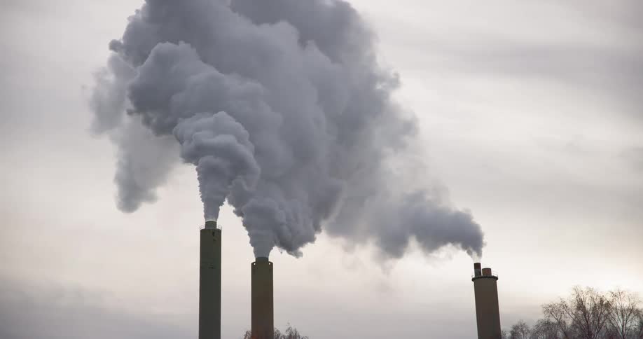 Thick smoke pours from tall smokestacks on a factory