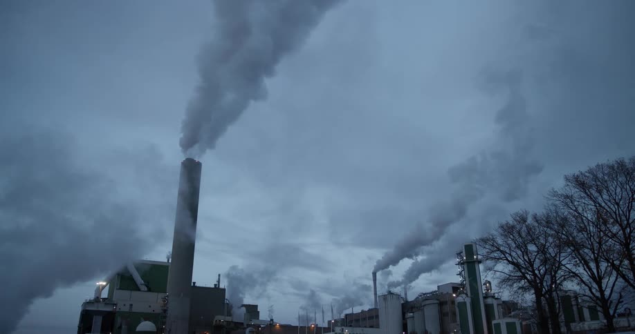 Factory releasing pollutants on a cloudy day with trees around