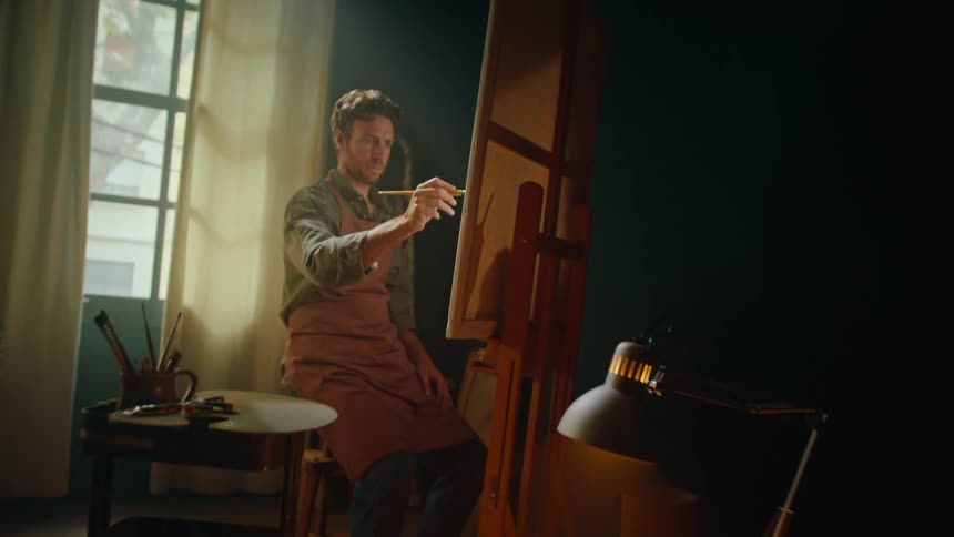 The man is painting in his studio