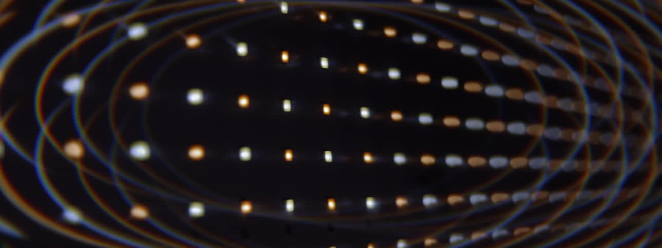 Abstract glowing light dots form symmetrical flowing patterns across a dark futuristic background