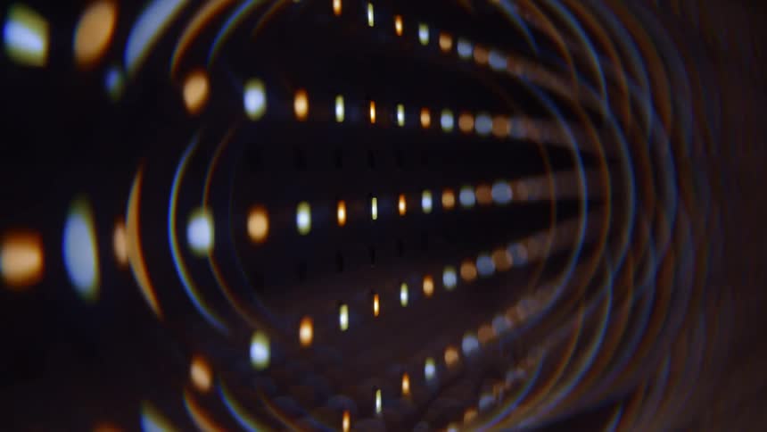 A close view of small yellow and white lights arranged in rows against a dark background with a circular reflection effect
