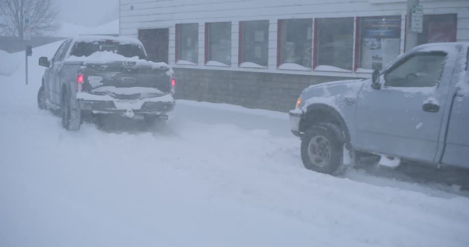 Pickup trucks on the street in front of a supermarket during a blizzard