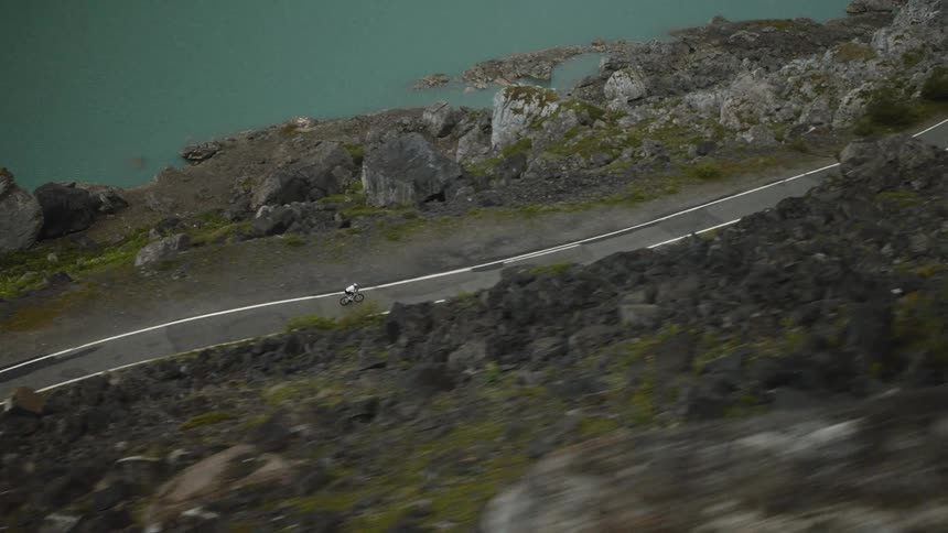 Man rides his bicycle on a mountainside road along the coast