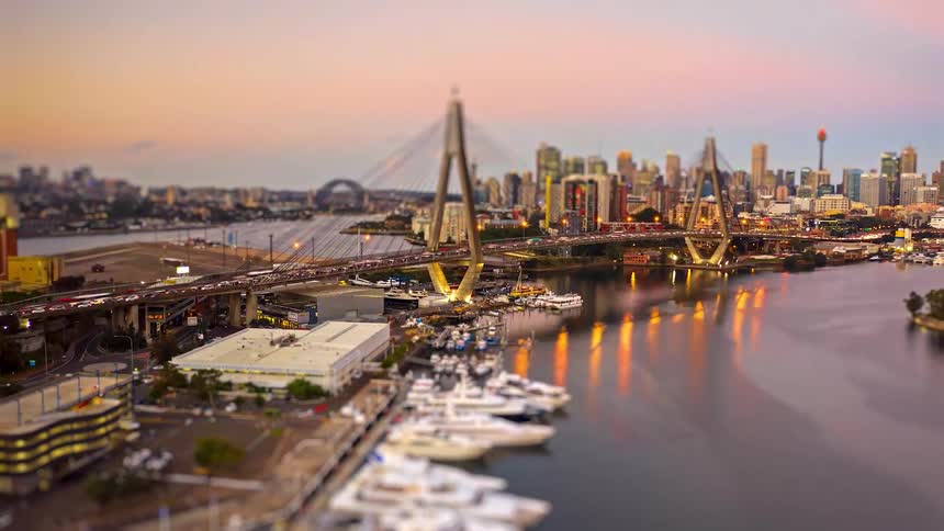 Cablestayed bridge over the river with a yacht marina in the foreground and an urban skyline in the background at dusk