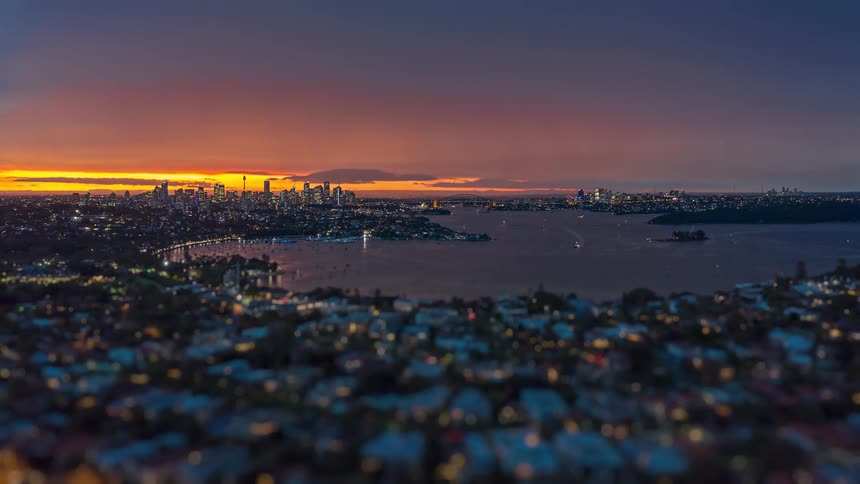Traffic moves through a harbor city as night falls