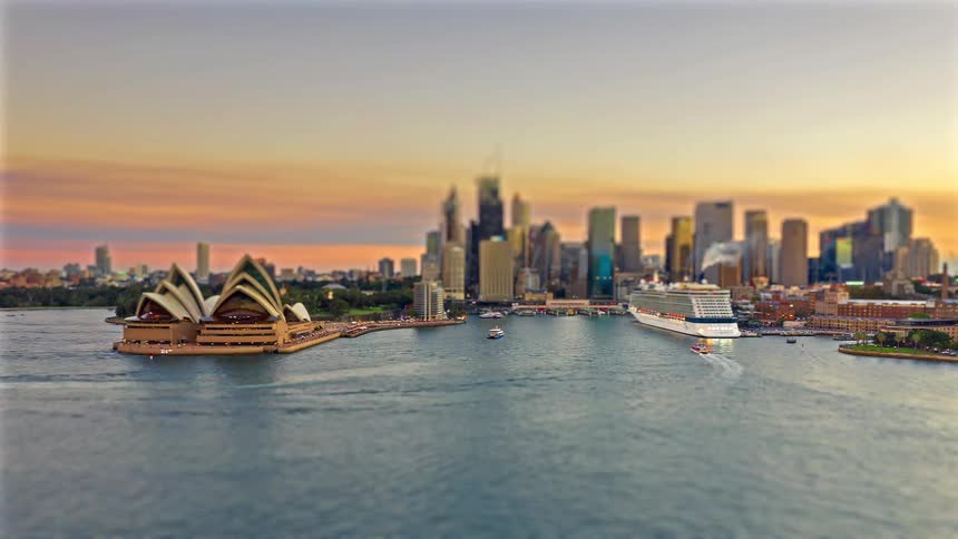 Aerial view of the sydney opera house and city skyline at dusk as boats move through the harbor
