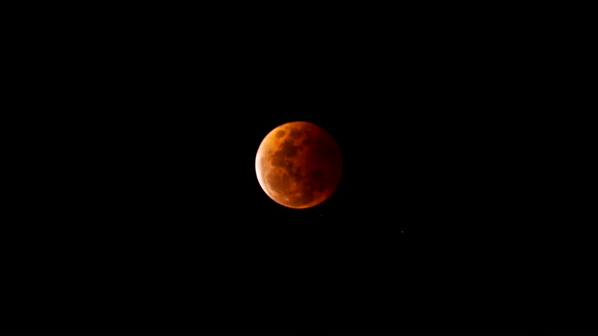 A lunar eclipse as the moon transitions through a deep red blood moon phase