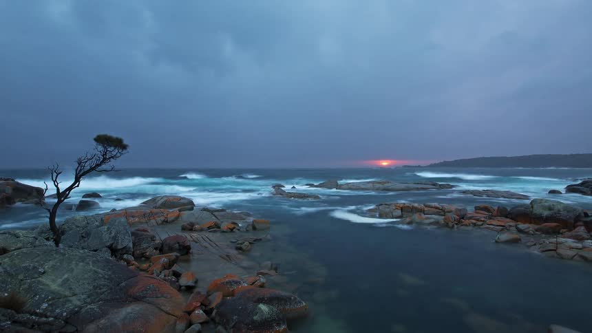 Clouds move across the sky above a rocky beach
