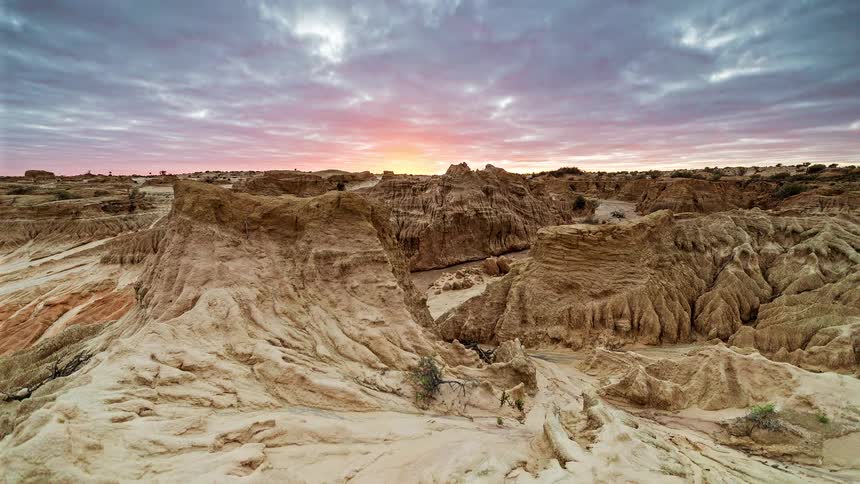 Clouds move over a canyon as the sun rises