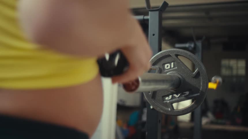 Pregnant woman removing a weight plate from a strength training machine
