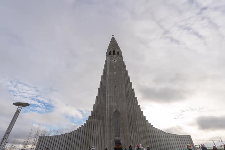 People walk in front of a church in reykjavik iceland with beautiful architecture