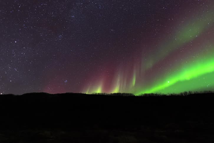 A view of a landscape with the aurora above it