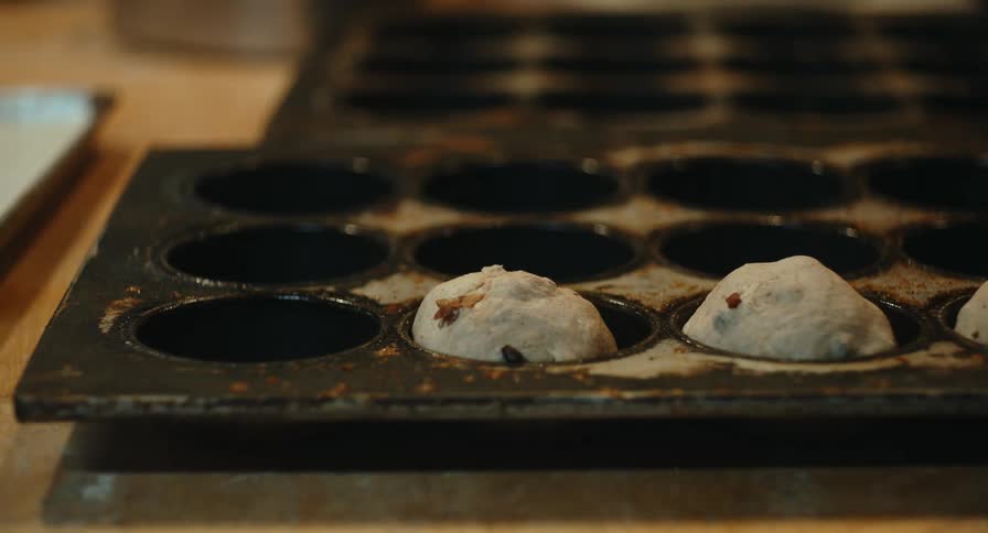 Baker puts dough into a cupcake pan