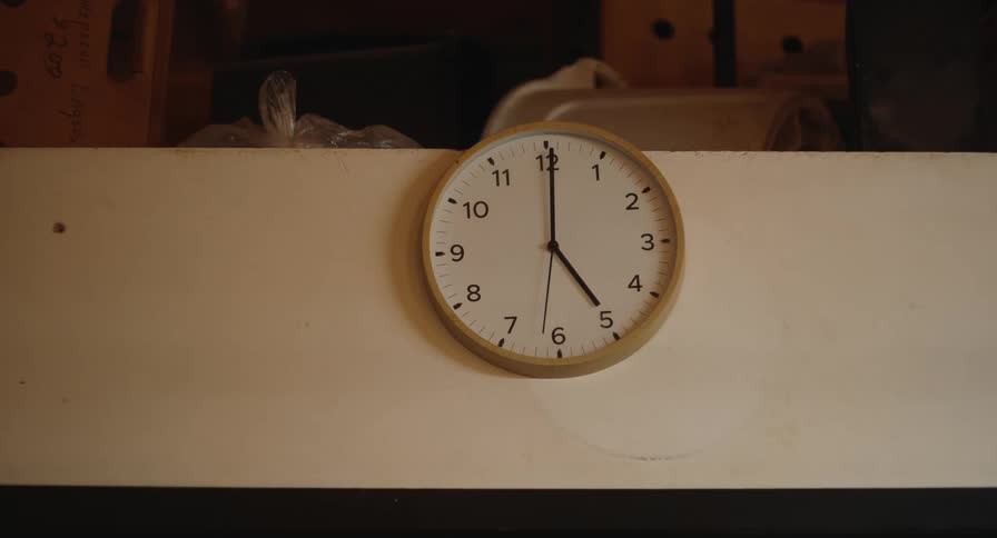 A wall mounted analog clock shows the time inside an indoor storage area